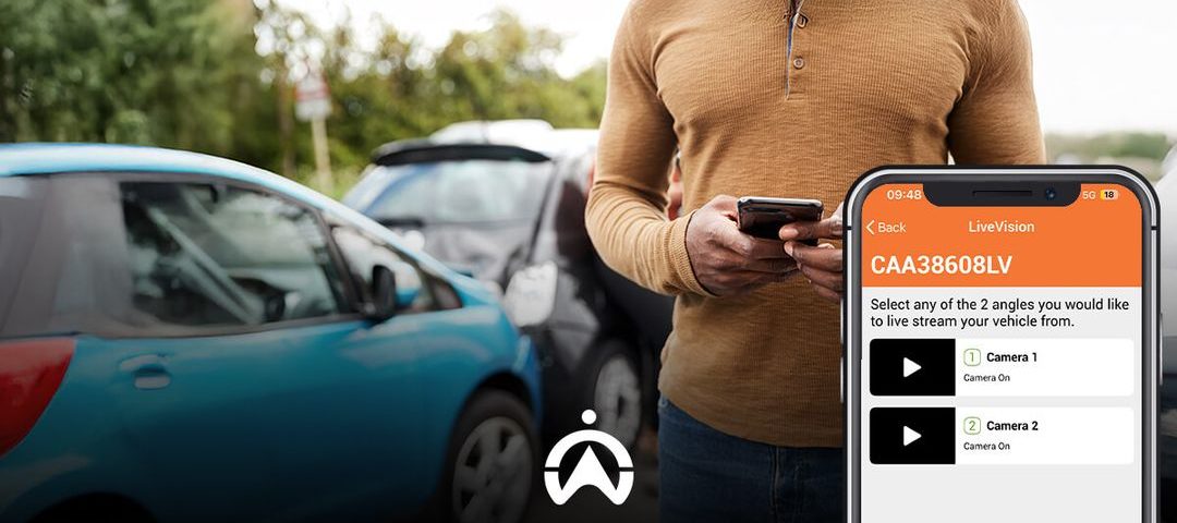 A person checks a mobile app to stream live video from their parked car, surrounded by vehicles in a parking lot.