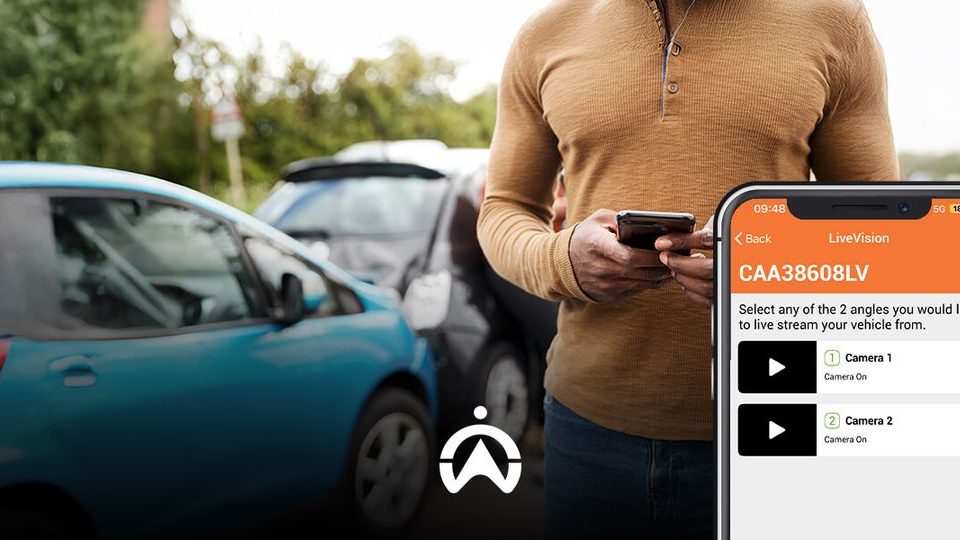 A person checks a mobile app to stream live video from their parked car, surrounded by vehicles in a parking lot.