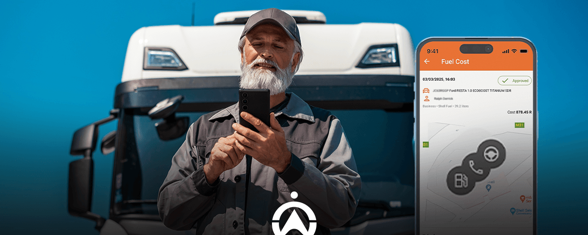 A man in a dark work uniform stands in front of a truck, holding a smartphone displaying a fuel cost app interface.