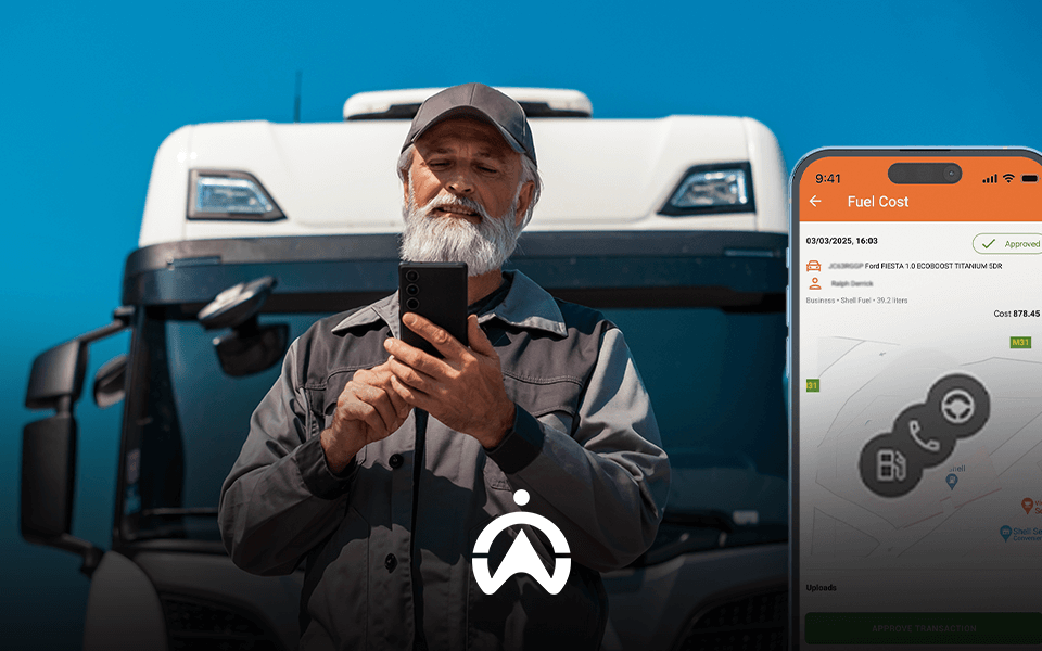 A man in a dark work uniform stands in front of a truck, holding a smartphone displaying a fuel cost app interface.