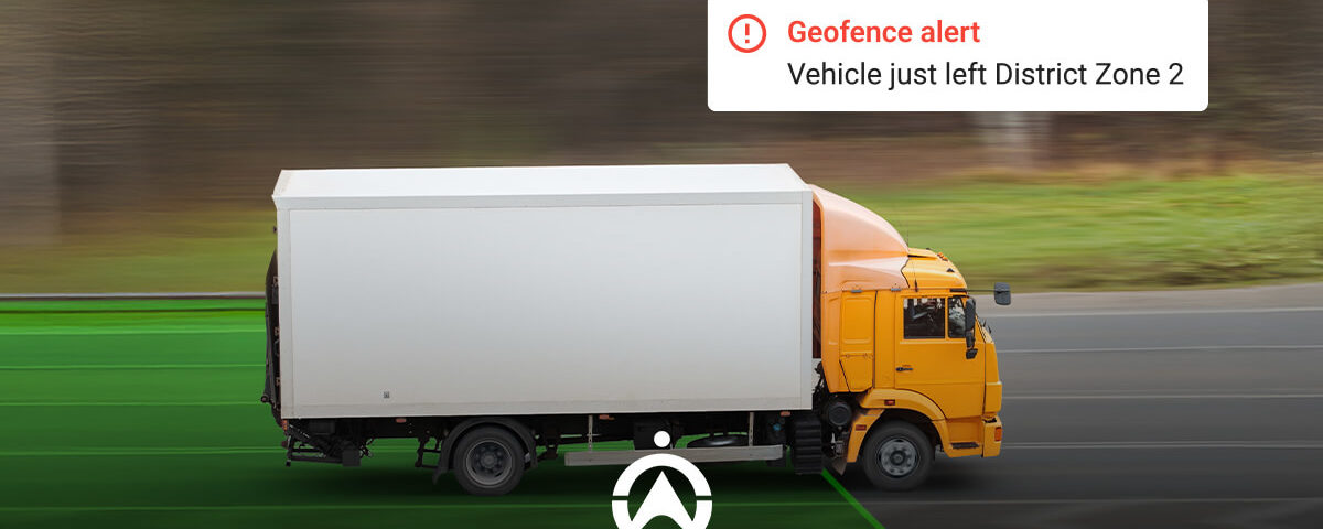 An orange truck exits a designated area, triggering a geofence alert on screen stating it left District Zone 2.