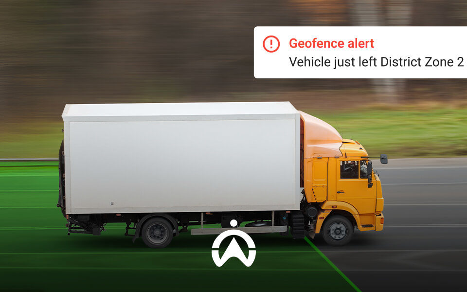 An orange truck exits a designated area, triggering a geofence alert on screen stating it left District Zone 2.